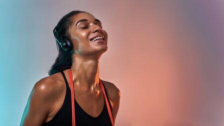 Music making me happy. Side view of smiling young woman in headphones holding jumping rope on...