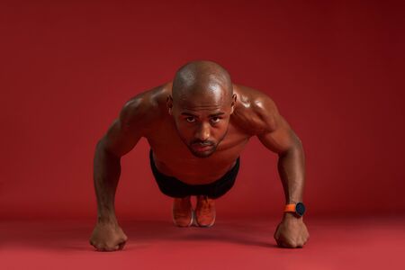 Healthier and stronger. Full length of strong african man in sports clothing doing push-ups isolated...