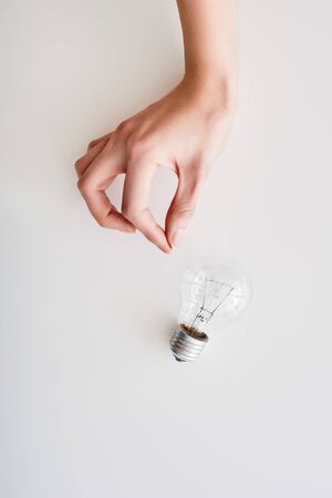 Female hand near an incandescent light bulbの写真素材