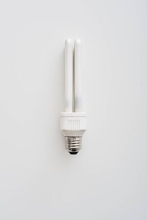 Energy saving light bulb lying vertically isolated on white background. Vertical shot
