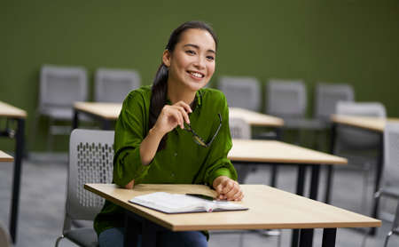 Business training. Young happy woman, female office worker sitting at desk in the office and...