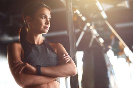 Fitness girl. Young attractive fit woman wearing sportswear keeping arms crossed and looking away...