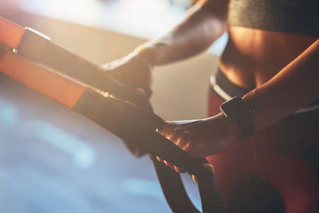 Close up shot of a woman exercising with fitness trx straps at gym, focus on female handの写真素材