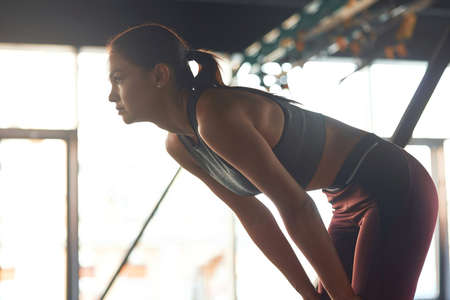 Feeling exhausted. Side view of a tired fitness woman resting after workout at gym, taking a breakの写真素材
