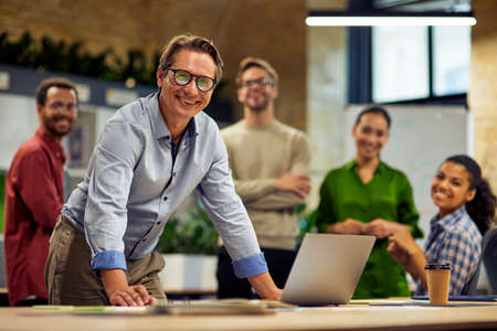 Group of young successful multi ethnic business team looking at camera and smiling while having a...