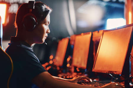 Male professional cybersport gamer wearing headphones playing online video game, participating in eSport tournamentの写真素材