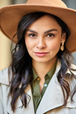 Young attractive caucasian woman wearing hat looking at camera while standing outdoors. Fashion, beautiful people conceptの写真素材