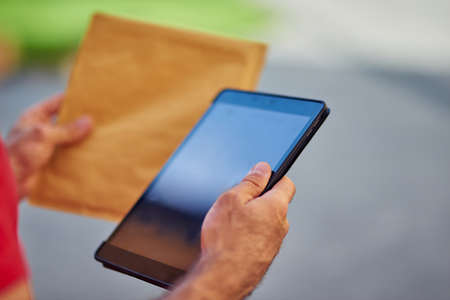 Digital tablet and paper packet in handsの写真素材