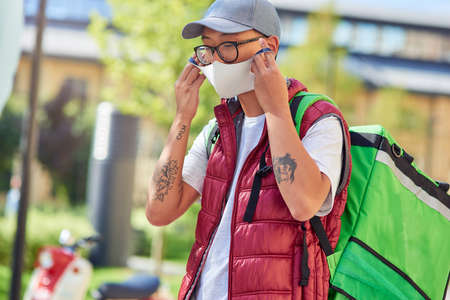 Young asian courier putting face mask onの写真素材