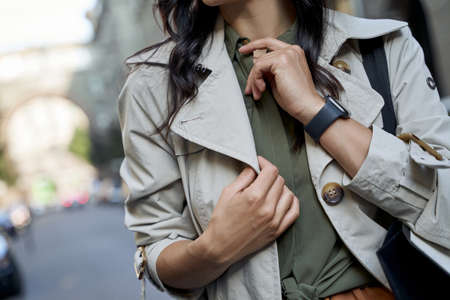 Cropped shot of a fashionable woman in grey coat standing on the city street