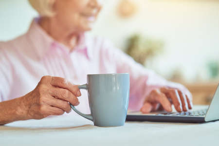 Close up of elderly lady holding cup of coffeeの写真素材