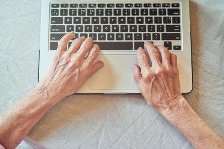 Cropped photo of elderly lady texting message at pc at home