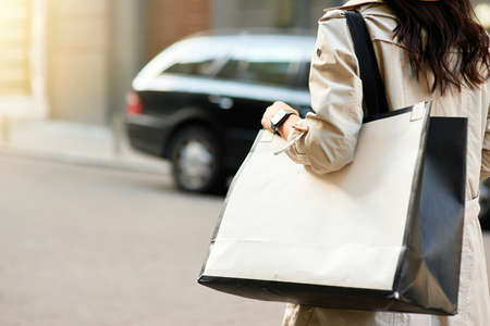 Cropped shot of woman carrying big shopping bag walking city streets