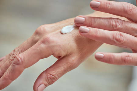 Middle aged woman hands applying cream