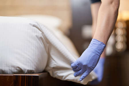 Female hands holding white sheet and making the bed