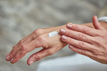 Beautiful female hands applying white creamの写真素材