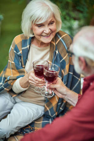 Smiling senior woman with plaid on her shoulders looking at spouseの写真素材