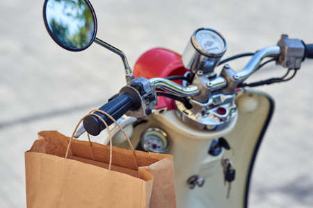 Paper bag hanging on scooter standing outdoors, selective focusの写真素材