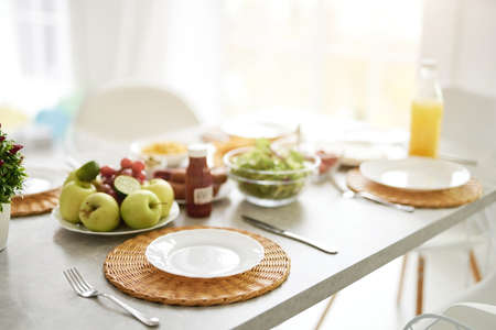 Start of the day. Close up of empty white plate and Latin style breakfast on the table. Modern bright white kitchen interior with wooden and white detailsの写真素材