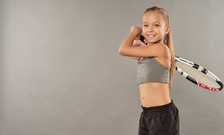 Cheerful female child in sportswear playing tennisの写真素材