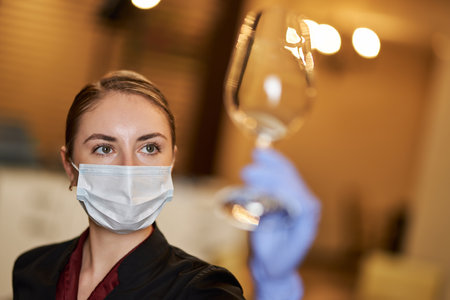 Meticulous waitress checking the cleanliness of glassの写真素材