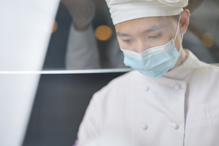 Thoughtful Asian cook being concentrated on workの写真素材