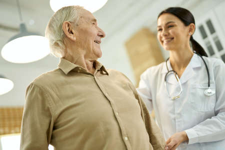 Cheerful aged man looking at his family doctorの写真素材