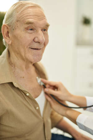 Gladsome senior man having his lungs listened to by doctorの写真素材