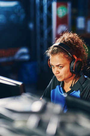 Young focused mixed race girl, female cybersport gamer wearing headphones participating in eSport...