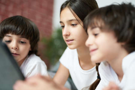 Real friendship. Close up of pretty teenage latin girl using digital tablet. Sister spending time...