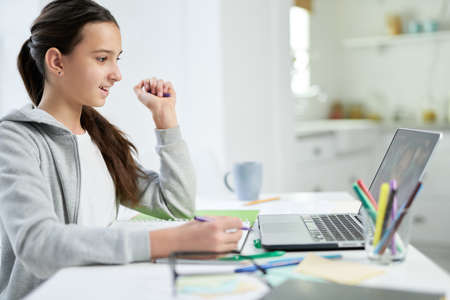 Unlimited learning. Cheerful latin teenage girl smiling, looking at the laptop screen, listening to...