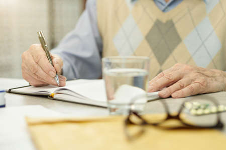 Elderly gentleman putting down important information on paper