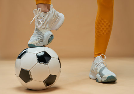 Female football player putting leg on the ballの写真素材
