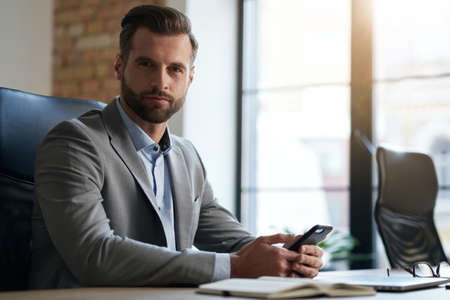 Reliable specialist sitting at his workplace in the officeの写真素材