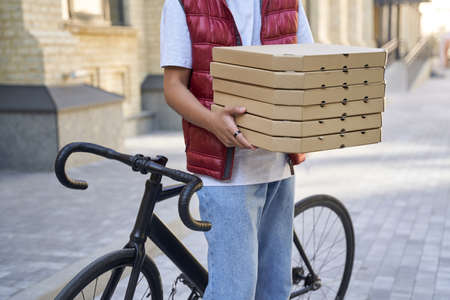 Cropped shot of a delivery man holding boxes with pizza while stの写真素材
