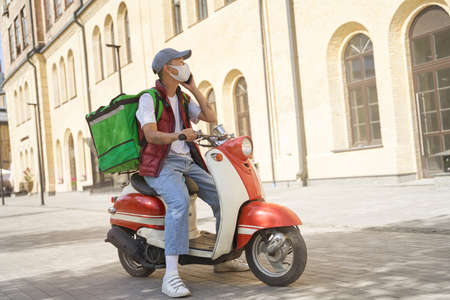 Young asian male courier with thermo bag wearing face protectiveの写真素材