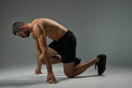 Adorable focused athlete man in shorts and sneakers taking a breather in room indoorsの写真素材