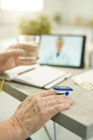 Senior citizen measuring vitals and consulting doctor online from homeの写真素材