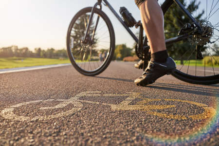 Close up of a bicycle sign drawn on asphalt. Professional male cyclist standing with his road bike on a cycle pathの写真素材