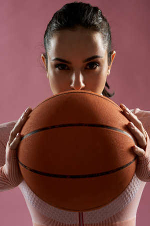 Attractive young woman holding orange basketball ballの写真素材