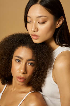 Beauty portrait of two gorgeous mixed race young women with perfect glowing skin posing together...
