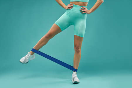 Fit young woman in sportswear using fitness bandの写真素材