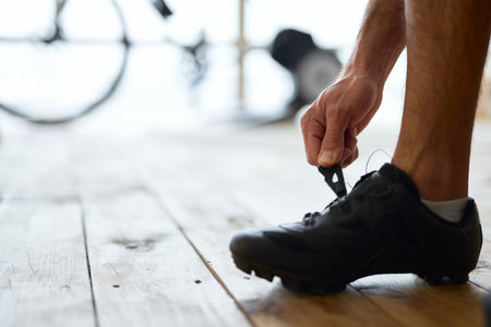 Young man putting on sports shoes before training at homeの写真素材