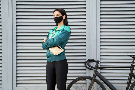 Lady in sportswear on a gray wall background
