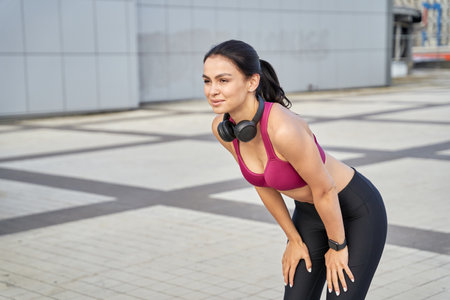 Beautiful athletic lady with wireless headphones during training