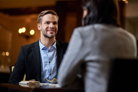 Gladsome gentleman sitting across table from a lovely ladyの写真素材