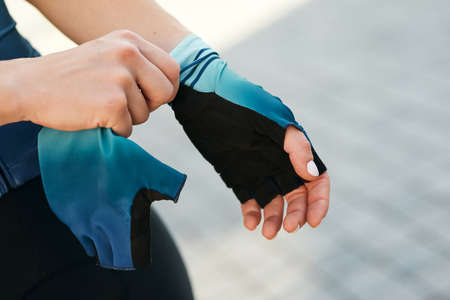 Close up shot of hands of professional female cyclist putting on cycling gloves while getting ready for trainingの写真素材