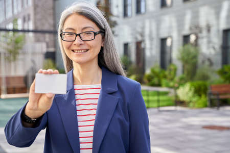 Mature business lady holding a blank plastic card and smilingの写真素材
