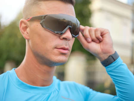 Portrait of young male cyclist putting on protective glasses, getting ready for cycling outdoorsの写真素材