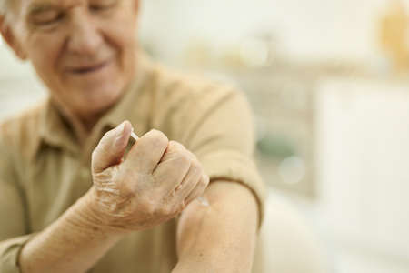 Focused senior gentleman making himslef arm injectionの写真素材